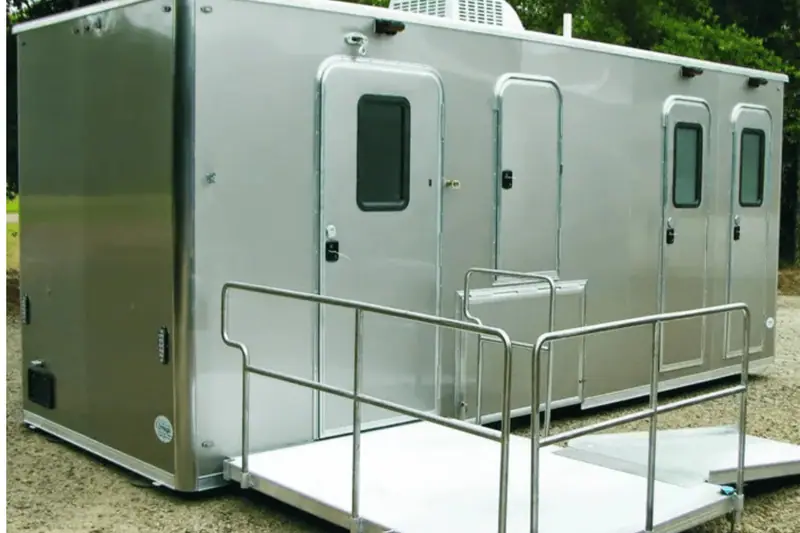 Silver restroom trailer with multiple doors and a ramp platform