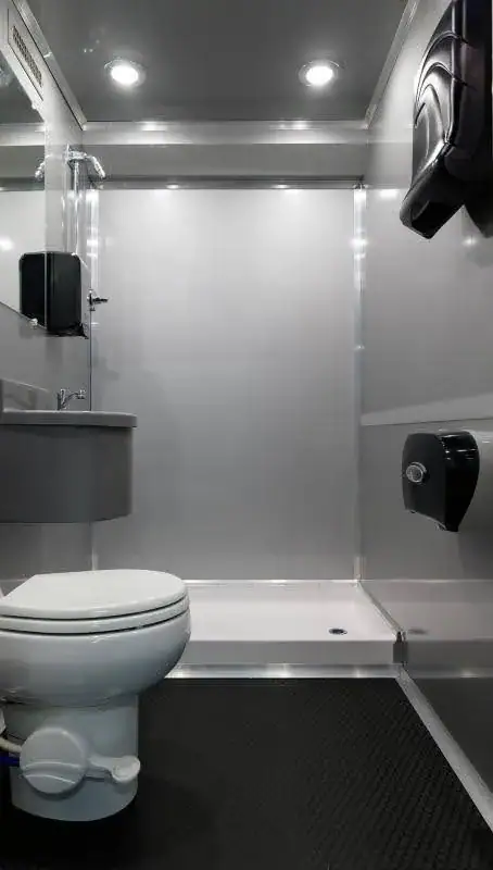 Shower and toilet room with a curtain, corner sink and paper towel dispenser