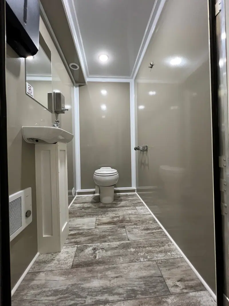 Private restroom with a toilet, pedestal sink and LED lights