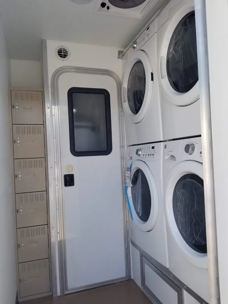Stacked washers and dryers inside a shower and laundry trailer