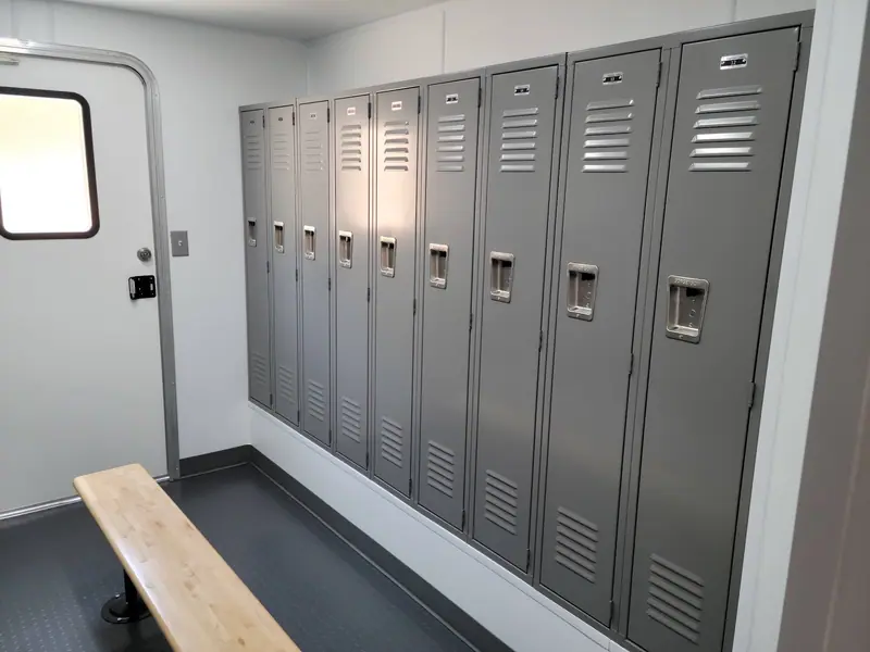 Locker room trailer with a row of metal lockers and a wooden bench