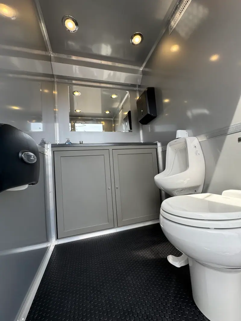 Men’s room with a toilet and urinal on a rubber coin floor