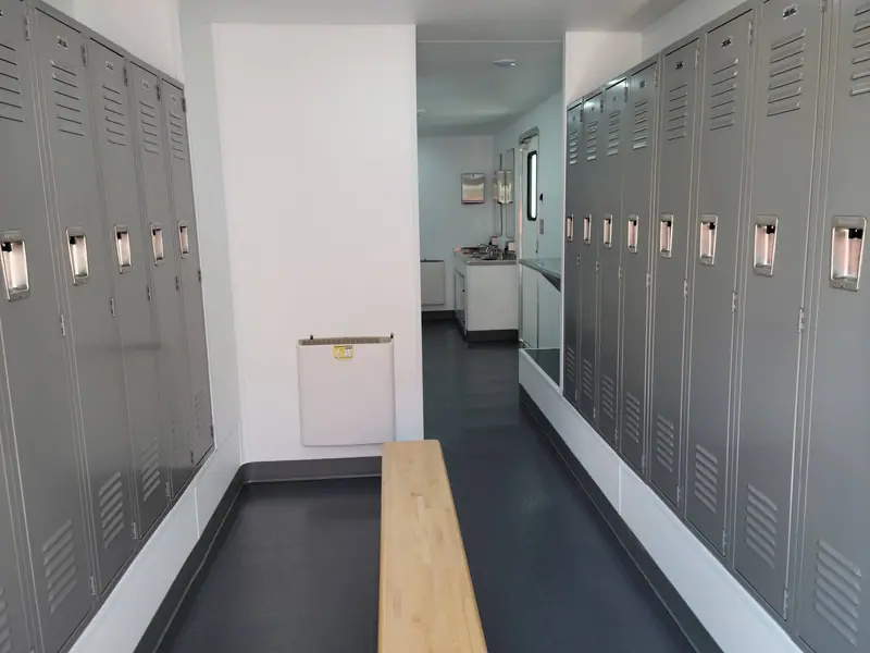 Locker room trailer with a long row of lockers and a wooden bench