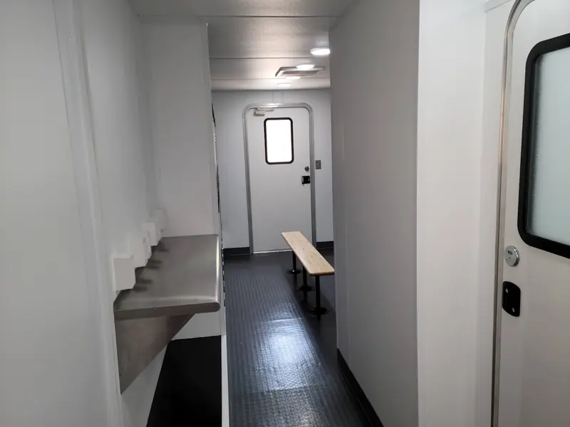 Stainless wash trough and a bench inside a locker room trailer