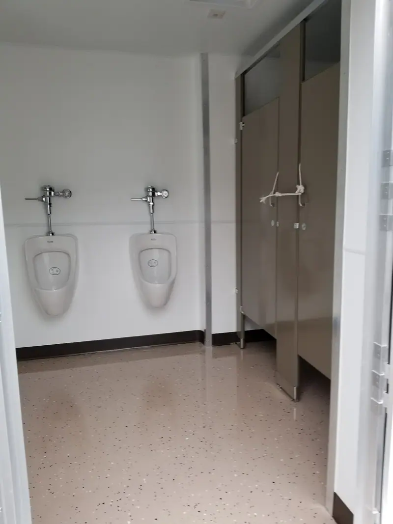 Men’s room with two urinals and a stall partition