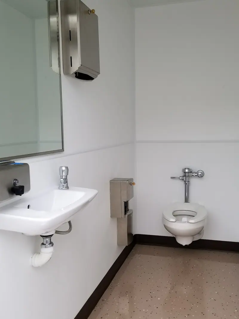 Restroom with a wall-hung sink and a commercial flush toilet