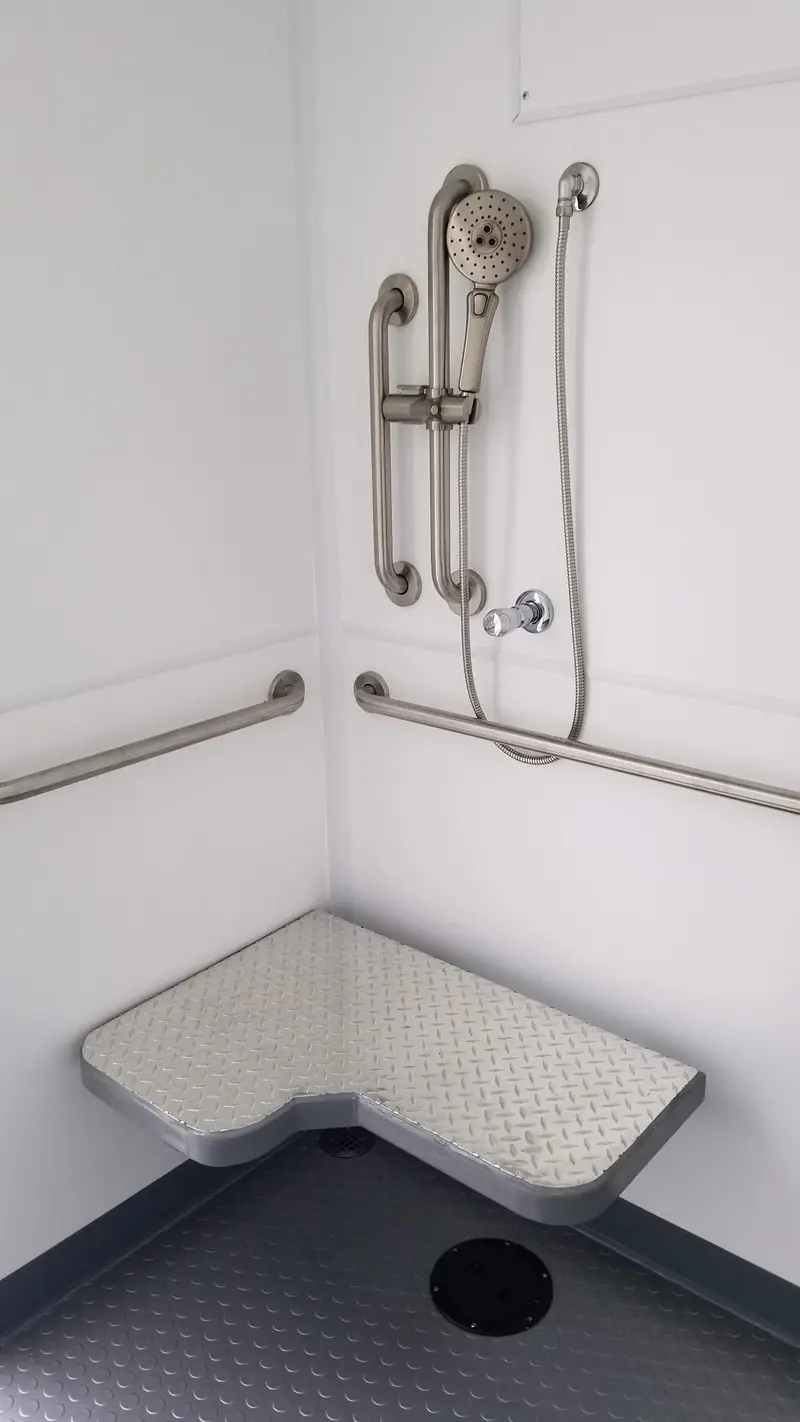 Shower with a hand-held sprayer, grab bars and a corner seat