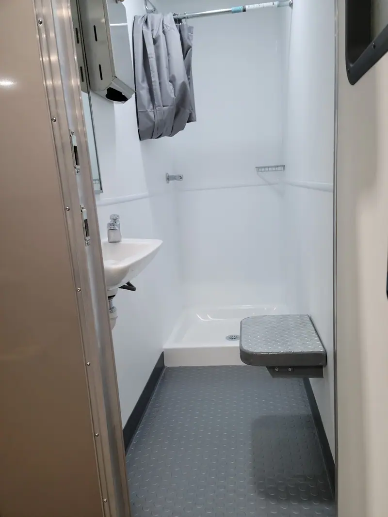 Private shower room with a fold-down bench and a towel hook