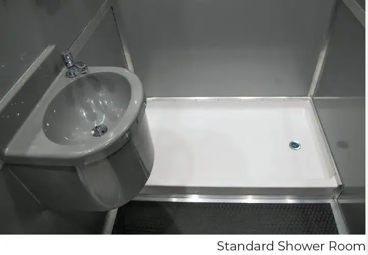 A compact 3 private room shower restroom and laundry trailer with a white wall-mounted sink and a rectangular shower tray featuring a right-side drain.