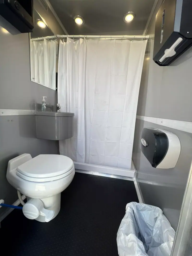 Combo room with a shower, toilet, sink and mirror behind one door