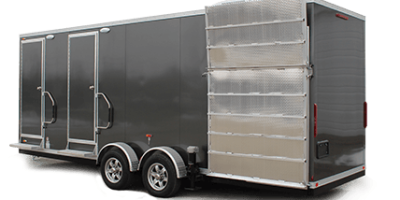 A large, gray, dual-axle shower restroom trailer with two entry doors on the side and a ramp-style door open at the rear.