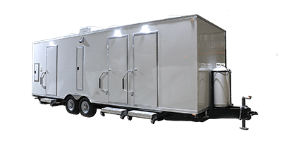 A large white shower restroom trailer with multiple doors, steps, and wheels is shown against a plain background.