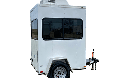 A small white shower restroom trailer with black-edged windows, a single axle, and an air conditioning unit mounted on the roof.