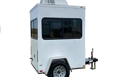 A small white shower restroom trailer with black-edged windows, a single axle, and an air conditioning unit mounted on the roof.